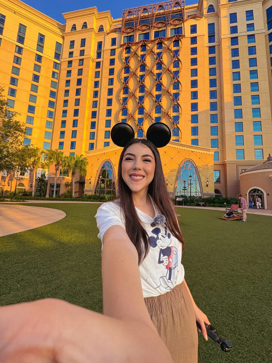 Dani Godinez con orejas de Mickey frente a un hotel de Walt Disney World.