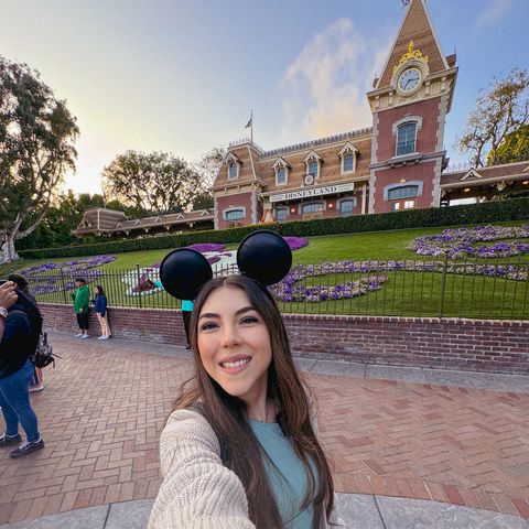 Dani Godinez frente a la estación del tren de Main Street y el jardín de Mickey en Disneyland