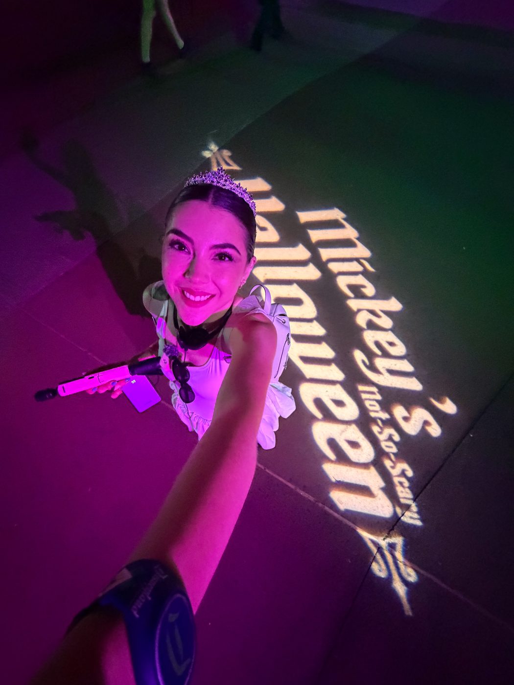 Dani Godinez de noche junto al logo de la Mickey's Not-So-Scary Halloween Party proyectado en el piso de Magic Kingdom.