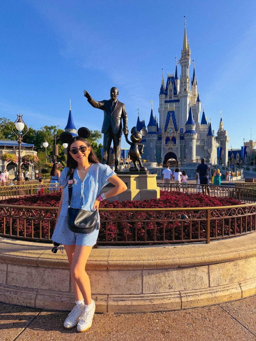 Dani Godinez frente a la estatua Partners de Walt Disney y Mickey y el Castillo de Cenicienta en Magic Kingdom, Walt Disney World