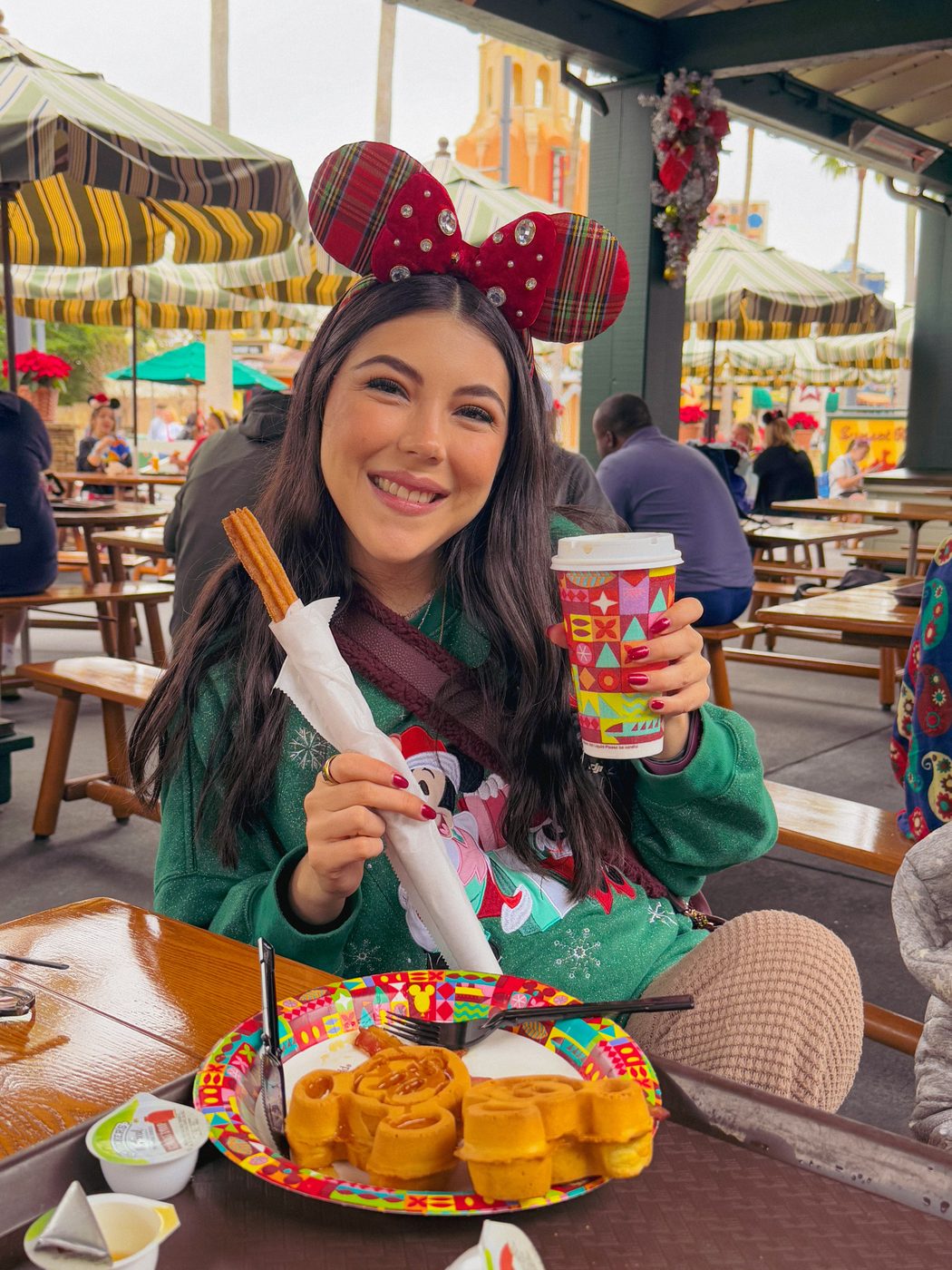 Dani Godinez con orejas de Minnie comiendo waffles de Mickey en un restaurante de servicio rápido de Walt Disney World.